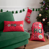 Rectangular red velvet cushion with candy-striped ground and "HoHoHo" slogan in ornate lettering with bauble motifs, shown on a green sofa beside a Christmas stocking and tree.