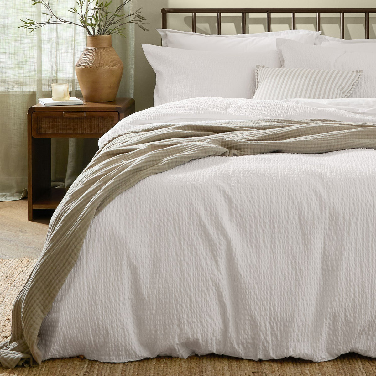 Hebden Cotton Plain Duvet Cover Set in Chalk white with seersucker texture, styled on a bed with white pillows and a striped throw in a bedroom setting.