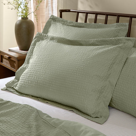Hebden Percale Cotton Pillowcase Pair in Bay Green with a textured seersucker face, shown styled on a bed with matching bedding in a bedroom setting.
