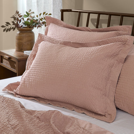 Hebden Percale Cotton Pillowcase Pair in dusky pink seersucker, shown styled on a bed with matching bedding in a bedroom setting.