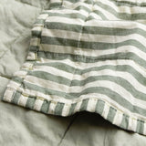 Close-up of the Hebden Percale Cotton Bedspread in Forest/Bay Green, showing the stitched edge where the green and white striped face meets the plain green cotton reverse.
