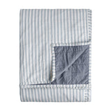 Hebden Percale Cotton Bedspread, folded to show reversible sides, one face with pale mineral blue and white stripes, the other in plain denim-blue quilted cotton, on a white background.