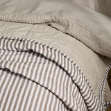 Hebden Percale Cotton Bedspread in Mole/Stone, folded to show mole-and-white stripe on one side and quilted stone reverse in square-grid stitching.