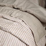 Hebden Percale Cotton Bedspread in Natural/Stone, close-up showing reversible beige-and-white striped side folded back over the plain stone cotton reverse.