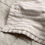 Hebden Percale Cotton Bedspread corner detail showing beige and white striped reverse against the plain stone quilted side, in 100% cotton.