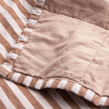 Close-up of the Hebden Percale Cotton Bedspread in Pecan/Cotta, showing the folded corner with pecan-brown striped cotton on one side and a plain blush reverse.