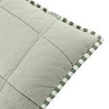 Close-up of the Hebden Percale Cotton Cushion in sage green, showing quilted grid-stitched fabric edged with green and cream striped piping.