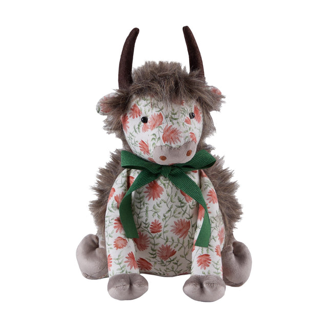 Hugo Polyester Door Stop shaped as a highland cow, with shaggy mane, dark curved horns, grey muzzle and paws, a coral floral print body tied with a green ribbon bow, on a plain white background.
