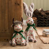 Hugo Polyester Door Stop shaped as a highland cow with shaggy mane, curved horns and cream floral fabric, tied with a green ribbon, shown beside a matching rabbit door stop.