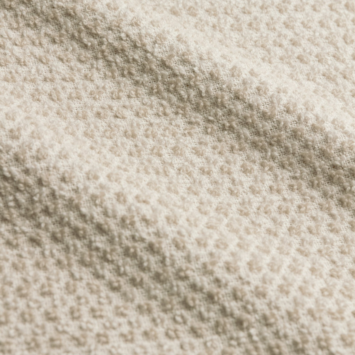Close-up of Hebden Plain Cotton Towels in stone, showing the textured waffle weave and honeycomb surface of the cream cotton fabric.