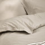 Close-up of the Hebden Cotton Plain Duvet Cover Set in Stone, showing washed cotton fabric in a soft grey-beige tone with a folded pillowcase edge.