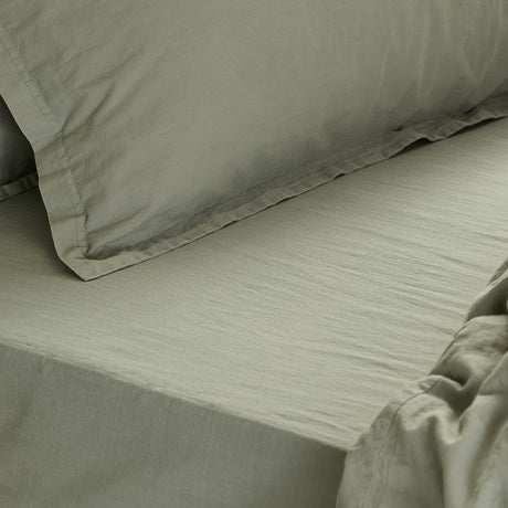Close-up of the Hebden Percale Cotton Fitted Sheet in bay green, showing its softly crinkled cotton weave with matching pillowcase on the bed.