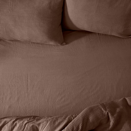 Hebden Percale Cotton Fitted Sheet in cocoa brown on a bed, shown with matching waffle-texture pillowcases and duvet in the same tone.
