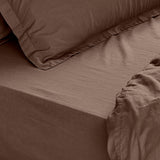 Close-up of the Hebden Percale Cotton Fitted Sheet in cocoa brown, showing the deep corner fit over a mattress with a matching crinkled pillowcase.