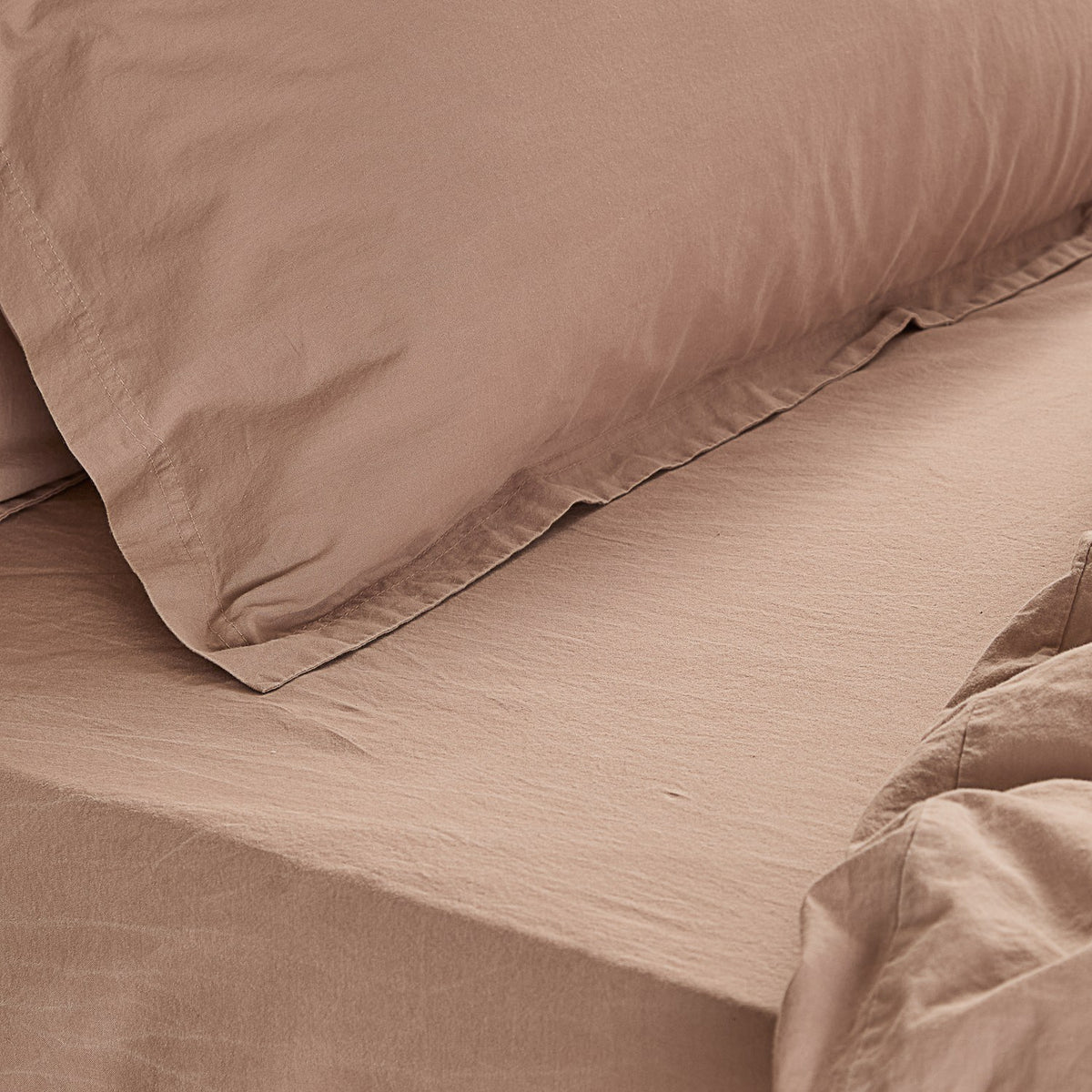 Close-up of the Hebden Percale Cotton Fitted Sheet in dusky pink, showing the crisp weave and matching pillowcase on a made bed.