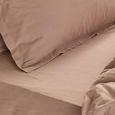Close-up of the Hebden Percale Cotton Fitted Sheet in dusky pink, showing the crisp weave and matching pillowcase on a made bed.