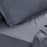 Close-up of the Hebden Percale Cotton Fitted Sheet in denim blue on a mattress, with a matching pillowcase showing the soft, textured cotton weave.