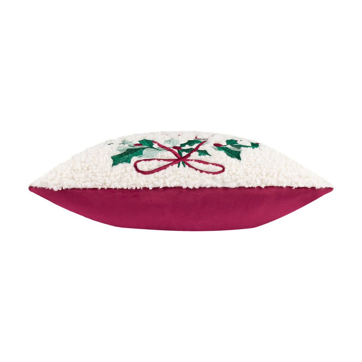 Side view of the Holly Wreath Bow Velvet Cushion showing cream bouclé fabric with embroidered holly and red bow trim above a magenta velvet base, on a white background.