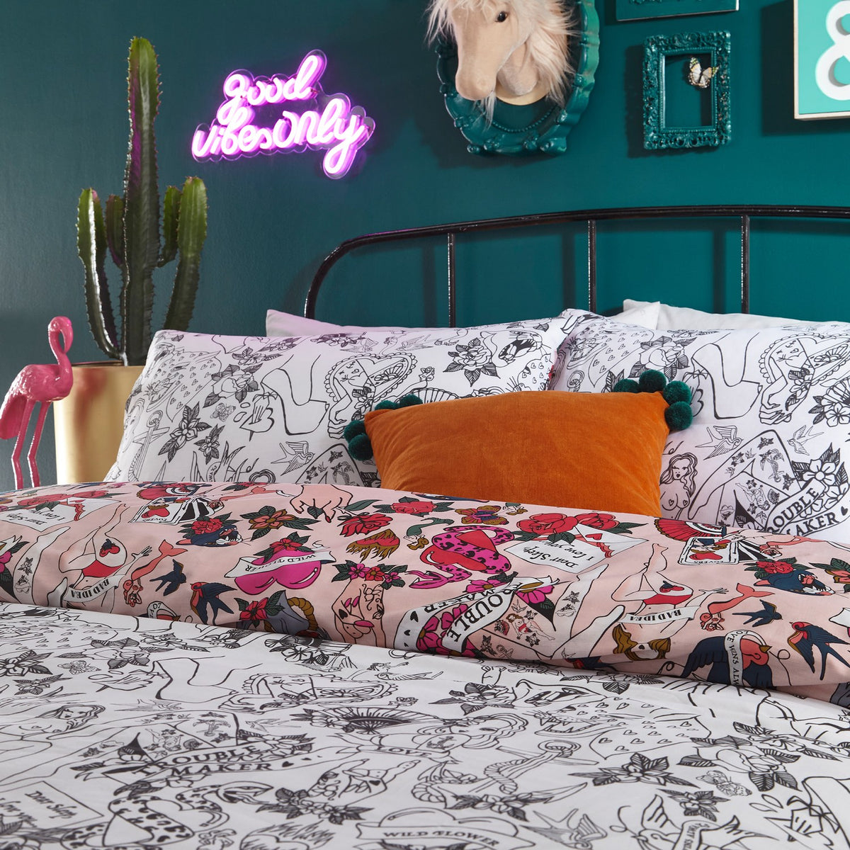 Inked Reversible Abstract Duvet Cover Set in Blush with tattoo-style pin-up and floral prints, reversing to a matching black and white line drawing, shown in a teal bedroom.