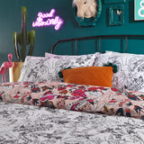 Inked Reversible Abstract Duvet Cover Set in Blush with tattoo-style pin-up and floral prints, reversing to a matching black and white line drawing, shown in a teal bedroom.