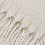 Close-up of the Isla Plain Polyester Throw in cream, showing its open woven texture and knotted tassel fringe edge.