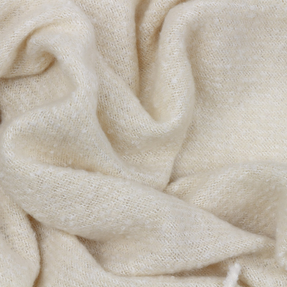 Close-up of the Isla Plain Polyester Throw in cream, showing its soft, loosely woven fabric with a brushed, textured surface.