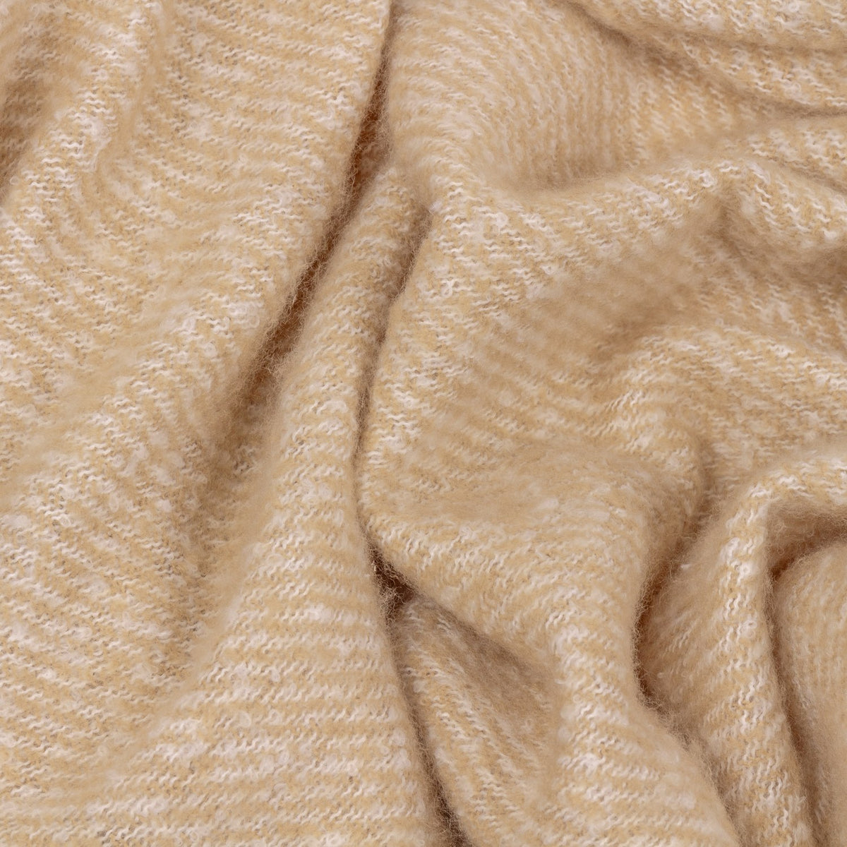 Isla Plain Polyester Throw in natural beige, shown draped in soft folds with a fine diagonal woven texture and cream flecks throughout.