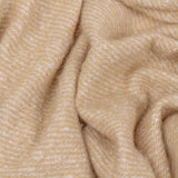Isla Plain Polyester Throw in natural beige, shown draped in soft folds with a fine diagonal woven texture and cream flecks throughout.