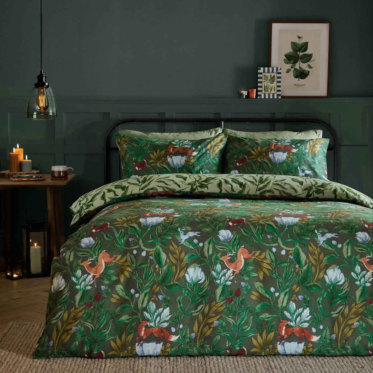 Into The Woods Reversible Leaf Duvet Cover Set in forest green on a bed, showing a woodland fox and hare print against a dark green bedroom wall.