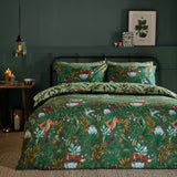 Into The Woods Reversible Leaf Duvet Cover Set in forest green on a bed, showing a woodland fox and hare print against a dark green bedroom wall.