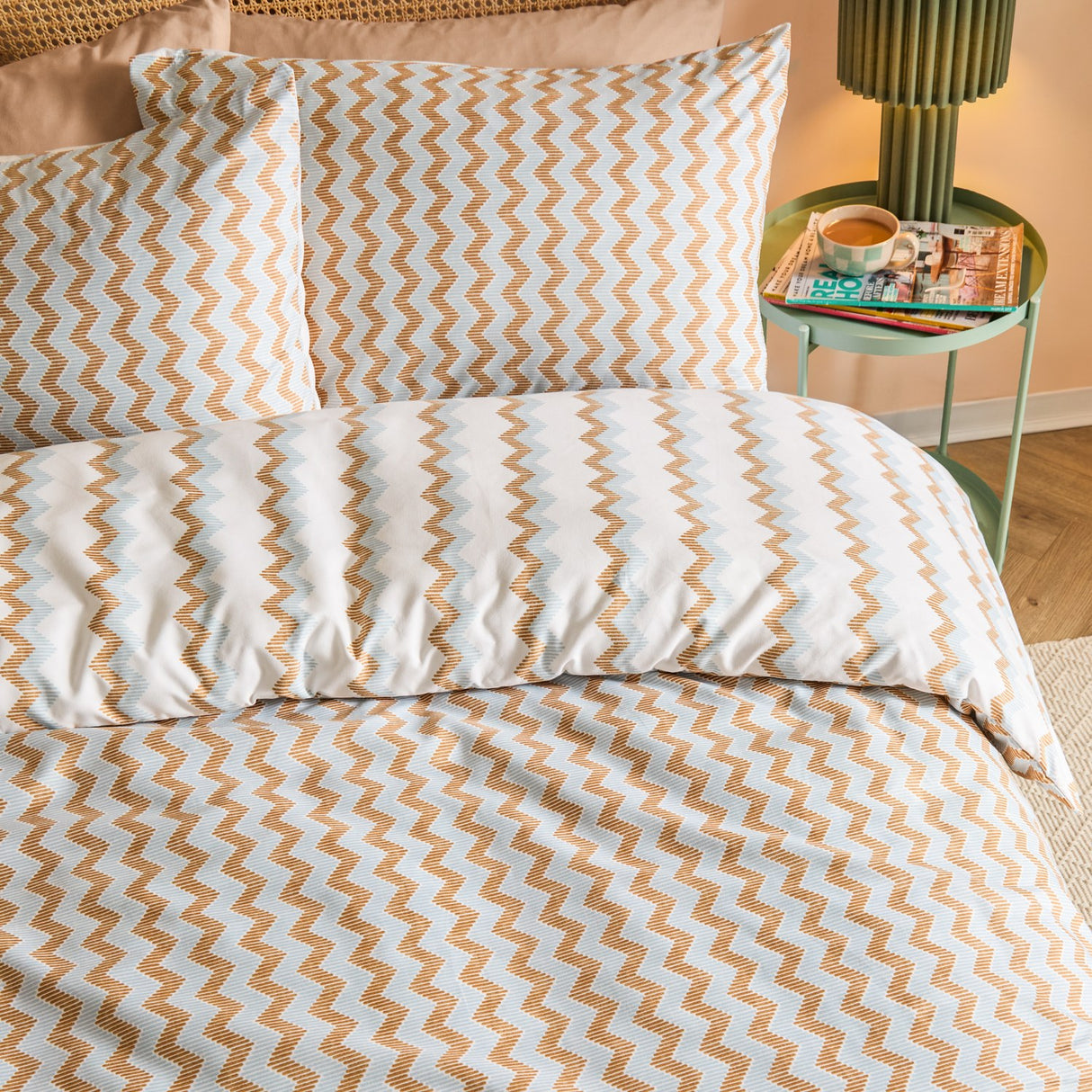 Izzie Reversible Striped Duvet Cover Set in blue and caramel zig-zag pattern, shown on a bed with matching pillowcases in a bedroom setting.