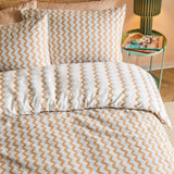 Izzie Reversible Striped Duvet Cover Set in blue and caramel zig-zag pattern, shown on a bed with matching pillowcases in a bedroom setting.
