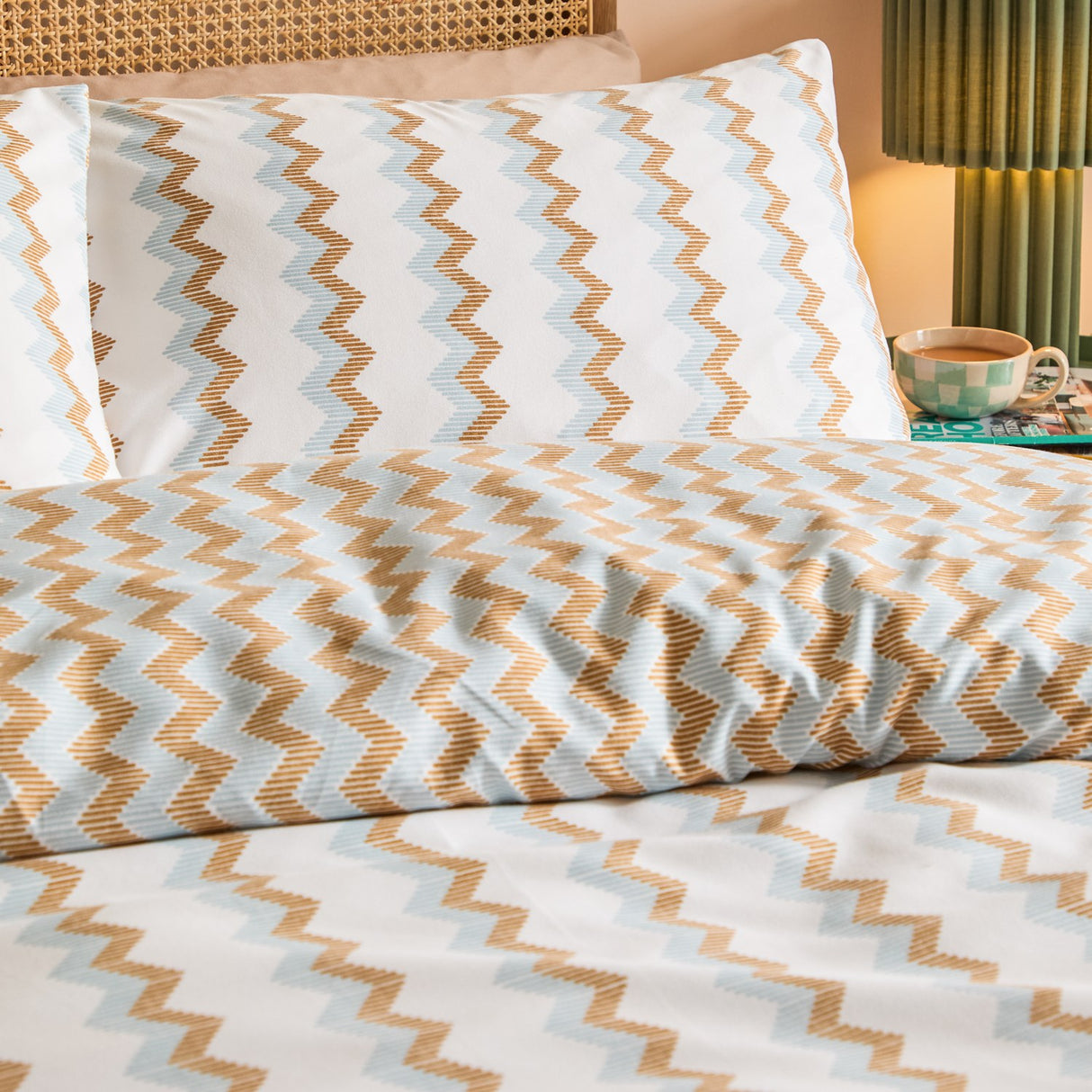 Izzie Reversible Striped Duvet Cover Set in blue and caramel zig-zag pattern, shown on a bed with matching pillowcases in a bedroom setting.