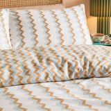 Izzie Reversible Striped Duvet Cover Set in blue and caramel zig-zag pattern, shown on a bed with matching pillowcases in a bedroom setting.
