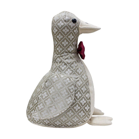 Duck-shaped door stop in grey and off-white jacquard floret pattern, with cream suede-feel beak, front and feet, a red bow tie at the neck, and black bead eyes, shown against a plain white background.