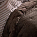 Jaye Velvet Cotton Bedspread in Bitter Chocolate, close-up of tufted brown velvet quilting beside a beige and white striped pillowcase.