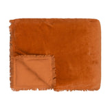Jaye Velvet Cotton Bedspread in rust orange, folded to show the plush velvet face with fringed edge trim and the smoother woven cotton reverse, on a plain white background.