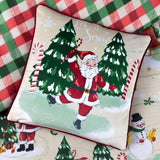 Multi 43x43cm velvet cushion with red piping, printed with a dancing Santa holding a candy cane, snowy trees, and Let it Snow text, on a plaid background.