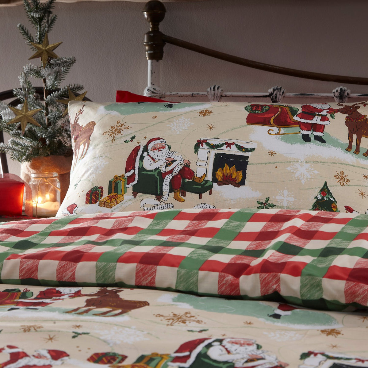 Jolly Santa Printed Gingham Duvet Cover Set in Multi, showing a cream pillowcase and duvet with Santa, reindeer and festive scenes, paired with a red and green check reverse, styled on a bed.