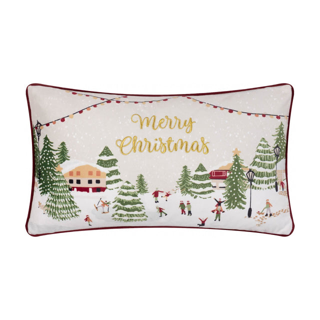Cream rectangular cushion embroidered with a snowy village scene, festive trees and figures, gold Merry Christmas text, and a berry red piped edge.