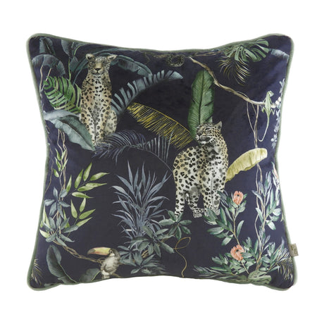 Square velvet cushion with a hand-painted jungle print of two leopards, banana leaves, ferns and a toucan on a dark ground, with petrol-toned piping, shown on a white background.