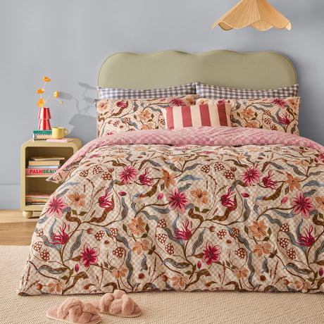Juno Reversible Check Duvet Cover Set in a bedroom setting, floral pink, coral and rust print on a check ground with striped and gingham cushions on a green upholstered bed.