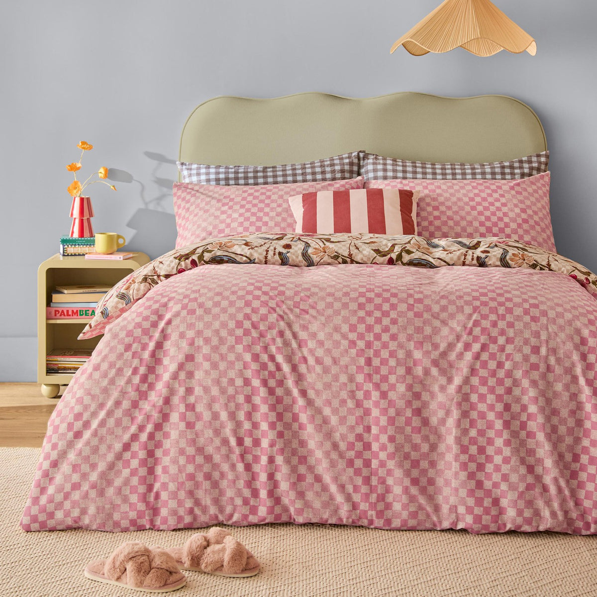 Juno Reversible Check Duvet Cover Set on a bed in pink and cream check with floral reverse trim, styled with striped and gingham cushions in a bedroom setting.