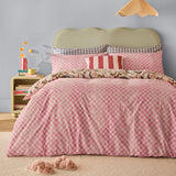 Juno Reversible Check Duvet Cover Set on a bed in pink and cream check with floral reverse trim, styled with striped and gingham cushions in a bedroom setting.