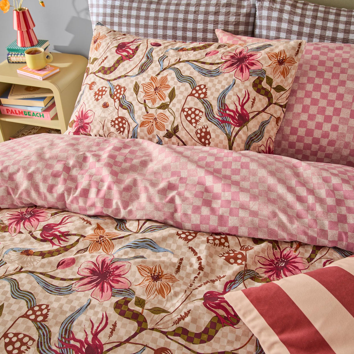Juno Reversible Check Duvet Cover Set in multicolour on a bedroom bed, showing a pink and cream floral check side paired with checked and gingham pillows.