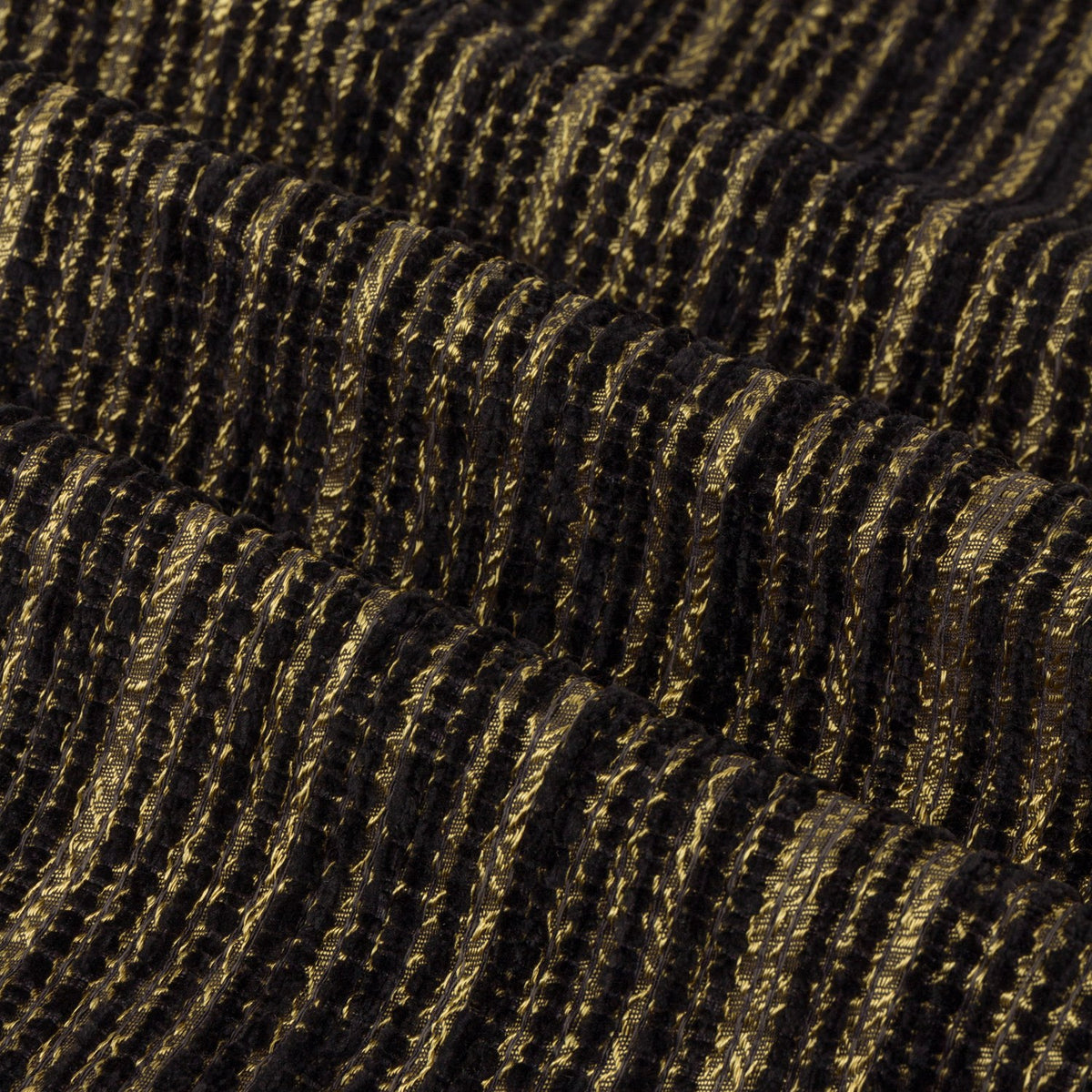 Close-up of the Jupiter chenille eyelet curtain fabric in black with fine horizontal gold thread detailing, showing a soft ribbed jacquard texture.