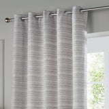 Jupiter Chenille Fully Lined Eyelet Curtains in silver, hung on a chrome pole with metal grommets, showing a fine horizontal woven texture beside a window.