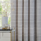 Jupiter Chenille Fully Lined Eyelet Curtains in Silver, shown in a striped grey and brown textured fabric hanging in soft folds beside a window in a living room setting.
