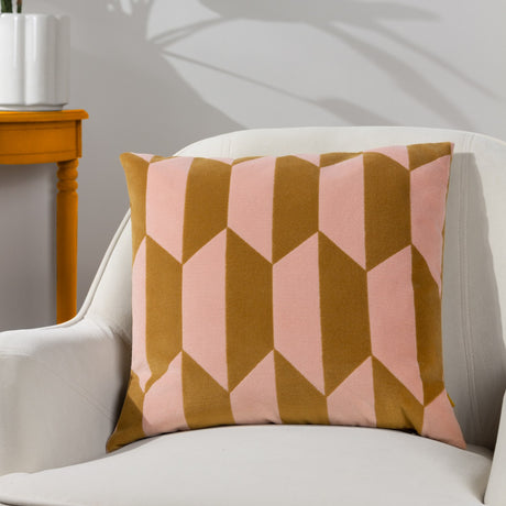 Kalho Jacquard Velvet Cushion in pink and ochre with a geometric tapering-block pattern, shown on a white armchair beside an ochre side table.