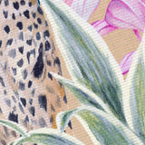 Close-up of the Kali Leopards polyester rug in gold, showing leopard-spot pattern, green leaf detailing, and pink floral accents on a flatweave base.